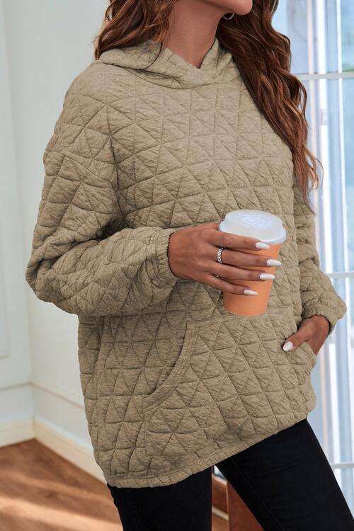 a woman holding a cup of coffee and wearing a quilted jacket