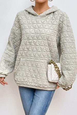 a woman in a gray sweater and jeans holding a white purse