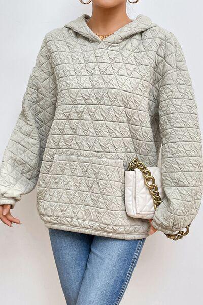 a woman in a gray sweater and jeans holding a white purse