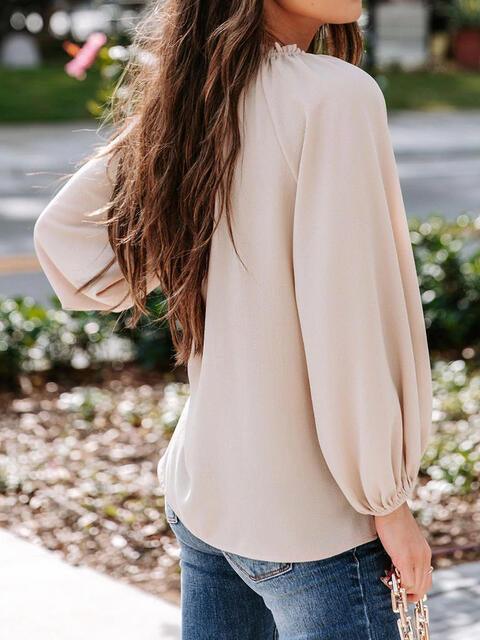 a woman with long hair wearing a tan blouse and jeans