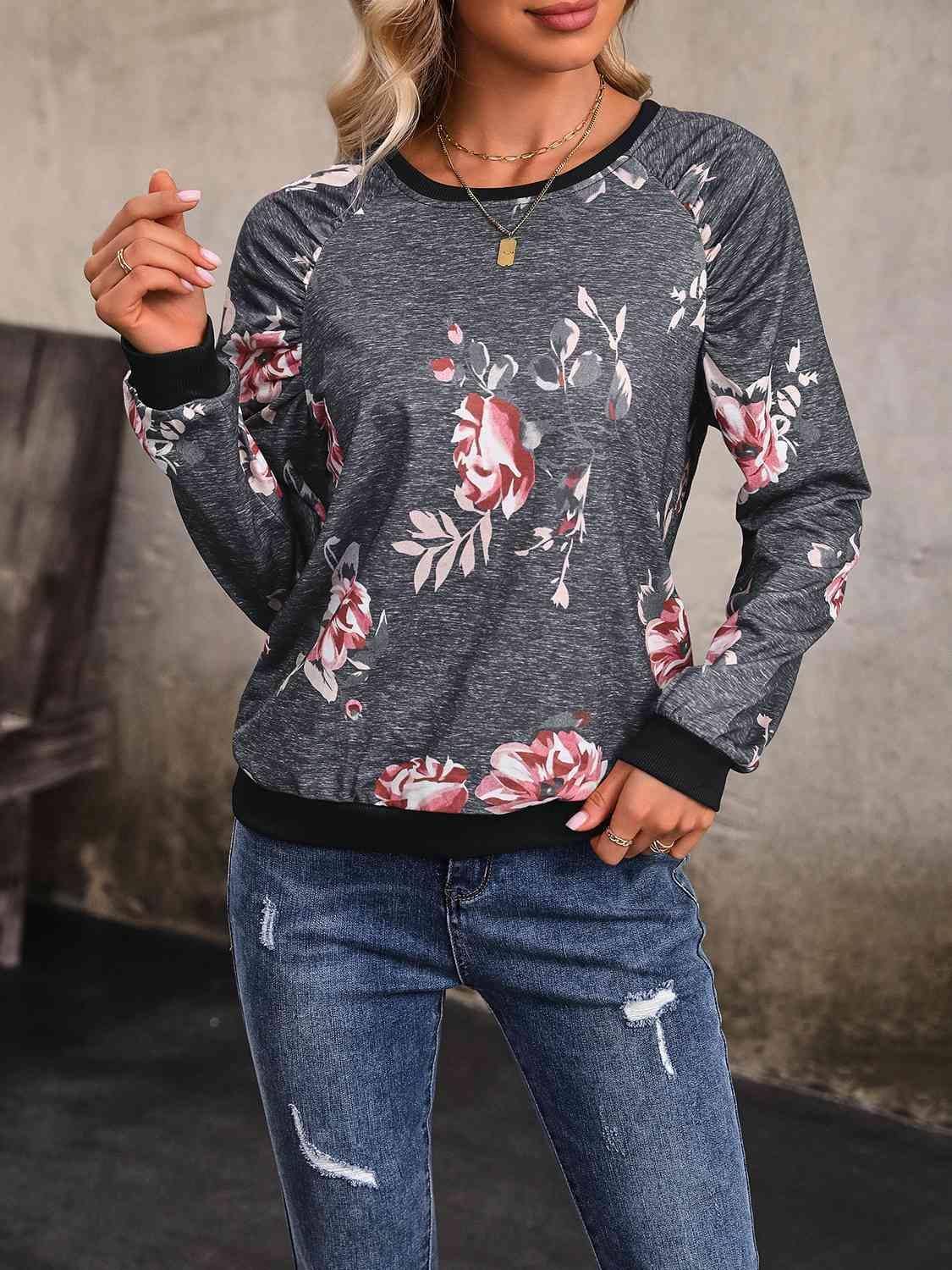 a woman wearing a floral sweatshirt and ripped jeans