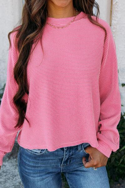 a woman wearing a pink sweater and jeans