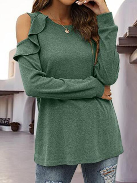 a woman wearing a green top and ripped jeans