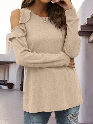 a woman wearing a tan sweater and ripped jeans