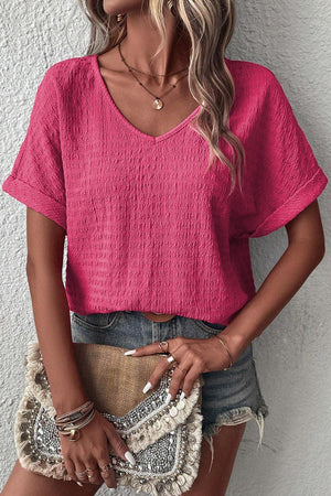 a woman wearing a pink top and denim shorts