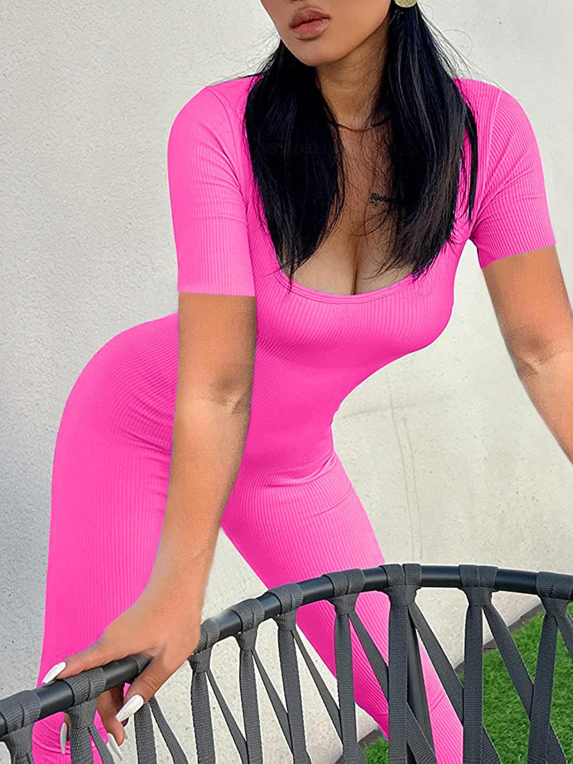 a woman in a pink outfit leaning on a fence