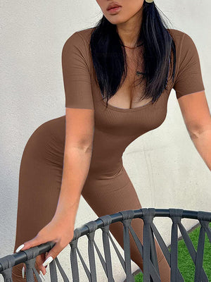 a woman in a brown outfit leaning on a fence