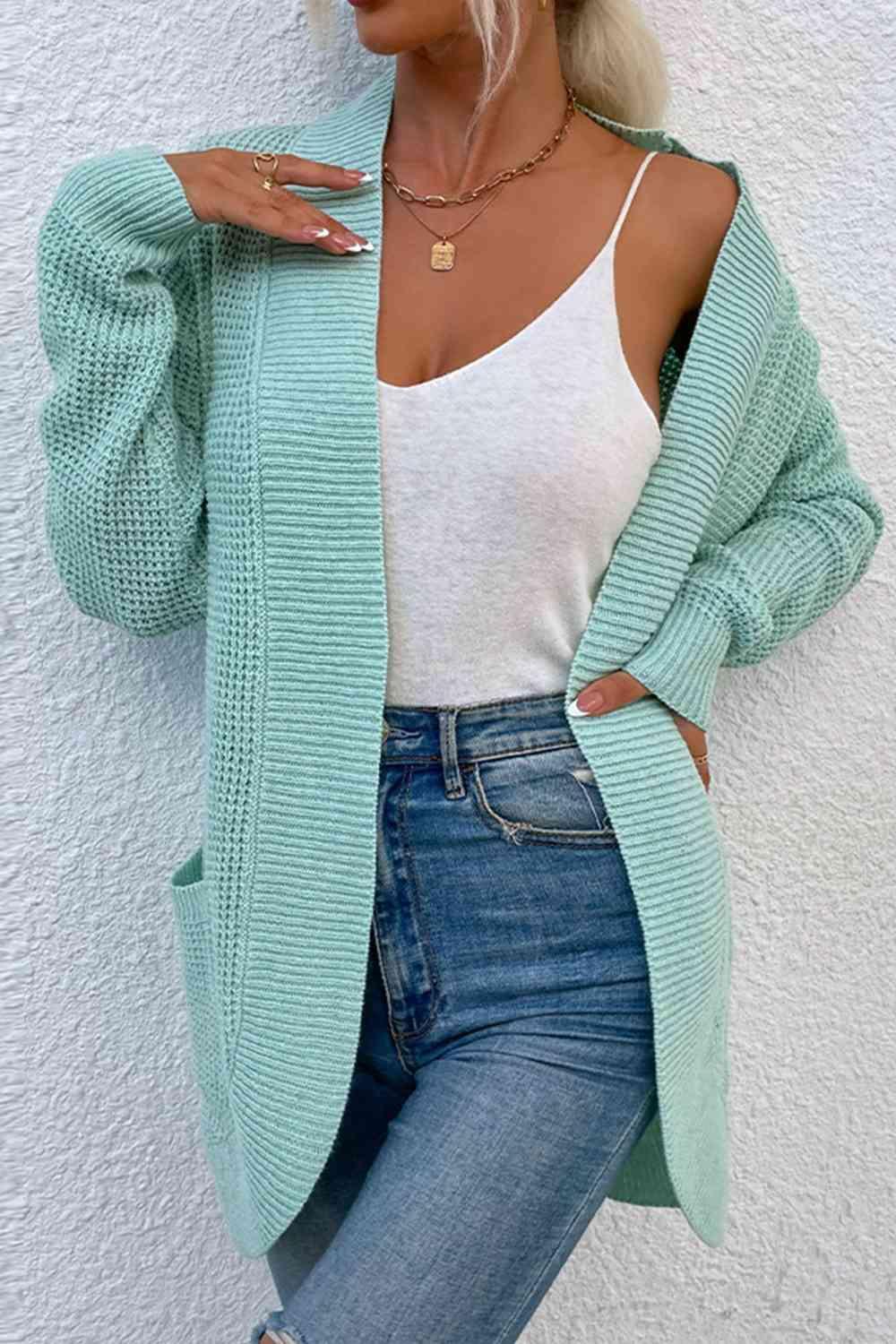 a woman wearing a green cardigan sweater and jeans