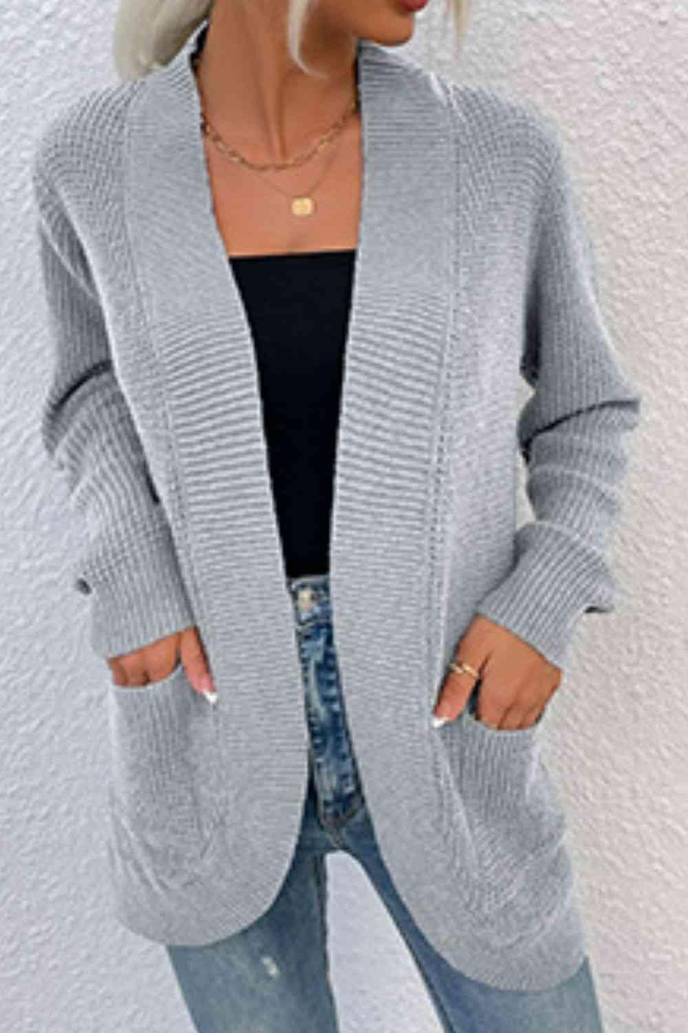 a woman wearing a gray cardigan sweater and jeans