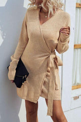 a woman leaning against a wall wearing a tan sweater dress