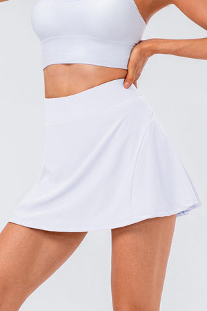 a woman in a white sports bra top and a white skirt