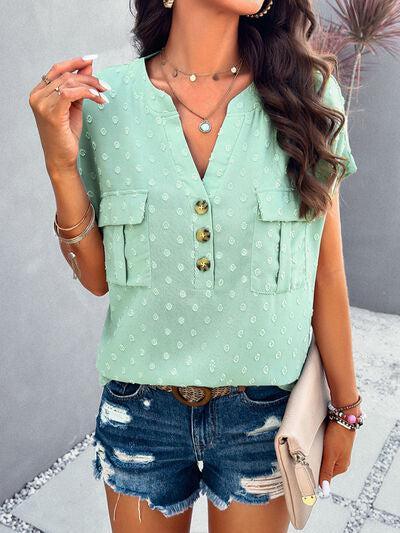 a woman wearing a green blouse and denim shorts