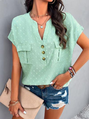 a woman wearing a green blouse and denim shorts