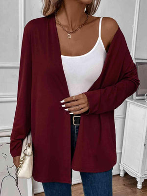 a woman wearing a white tank top and a burgundy cardigan