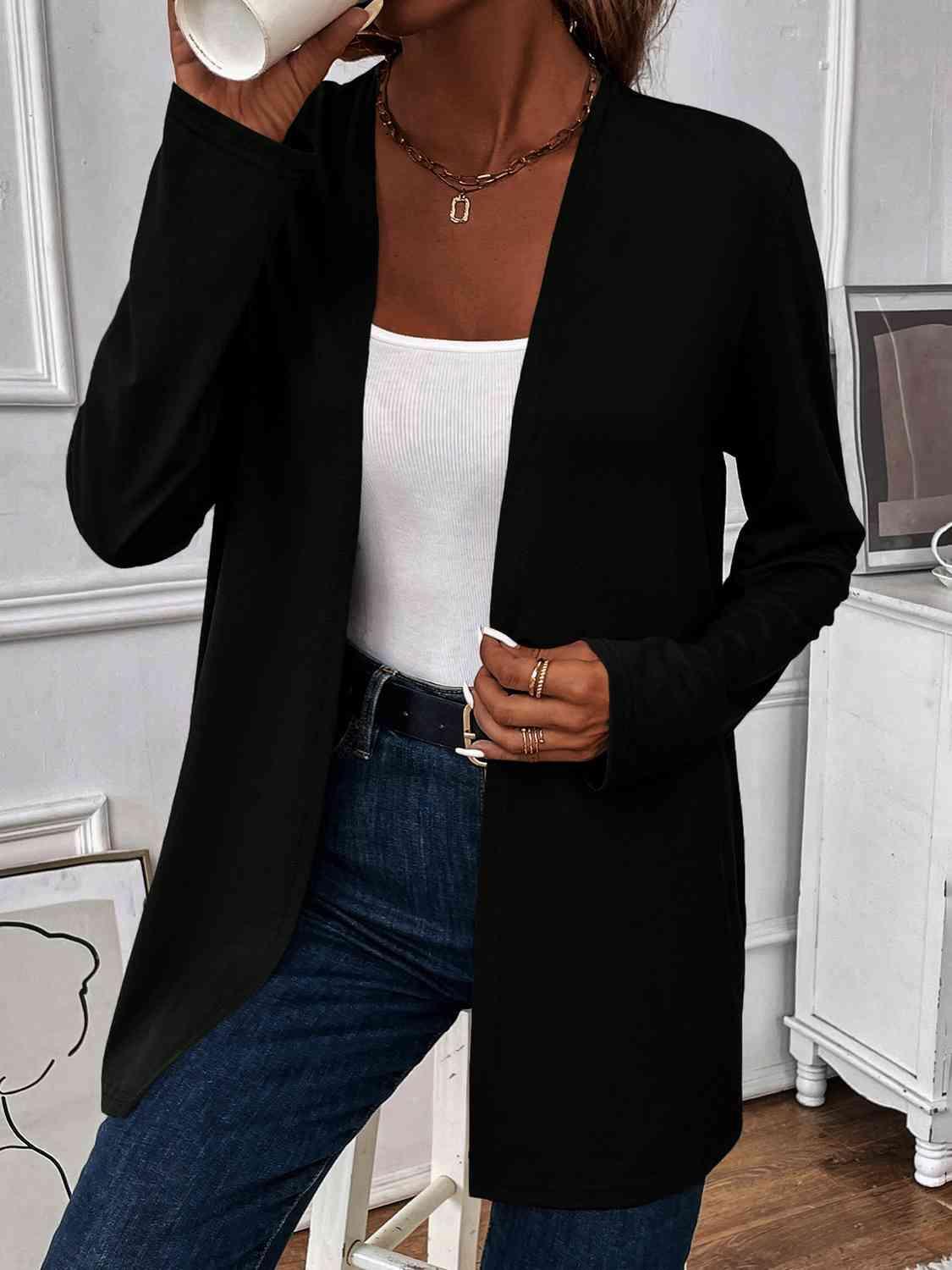 a woman drinking from a cup while wearing a black cardigan