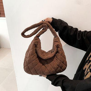 a woman holding a brown purse in her hand