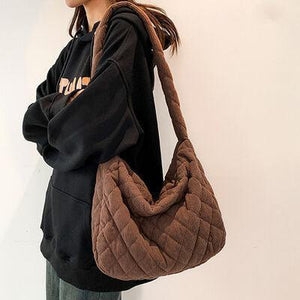 a woman holding a brown purse standing next to a white wall