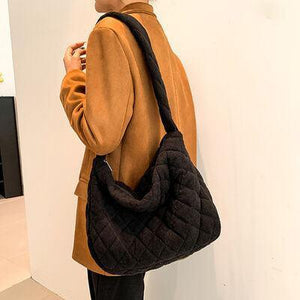 a woman standing next to a white wall holding a black purse