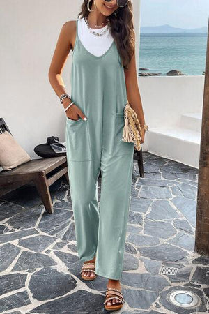 a woman wearing a green jumpsuit and sandals