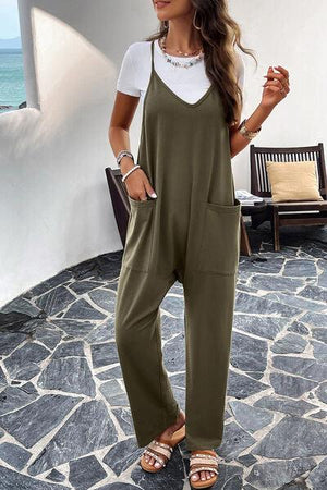 a woman wearing a green jumpsuit and sandals