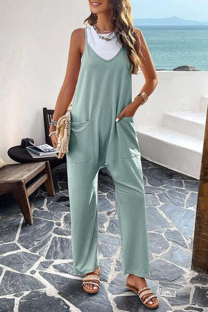 a woman wearing a green jumpsuit and sandals