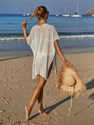 a woman walking on a beach carrying a straw hat