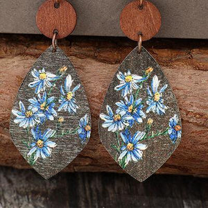 a pair of wooden earrings with blue flowers painted on them