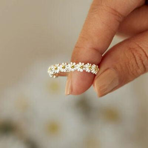 a woman's hand holding a ring with daisies on it