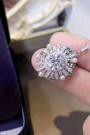 a woman's hand holding a diamond and emerald ring