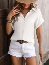 a woman wearing a straw hat leaning against a wall