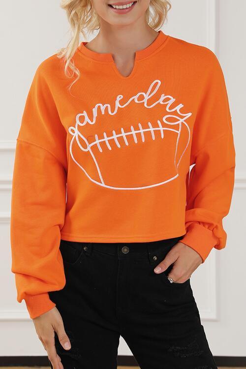 a woman wearing an orange sweatshirt with a football on it