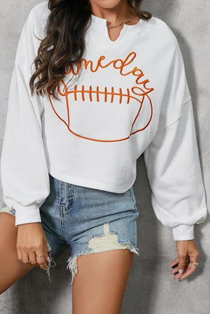 a woman wearing a white sweatshirt with a football on it