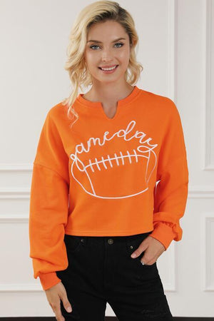 a woman wearing an orange sweatshirt with a football on it