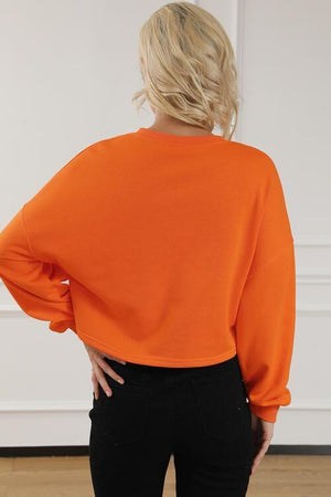 a woman wearing an orange top and black pants