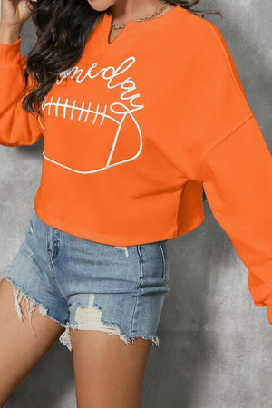 a woman wearing an orange sweatshirt and ripped shorts
