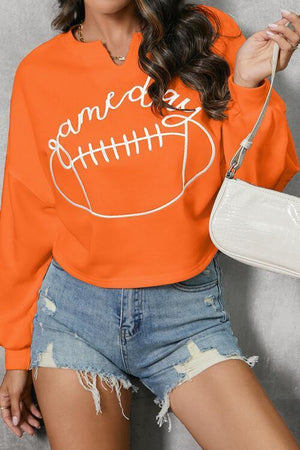 a woman wearing an orange sweatshirt with a football on it