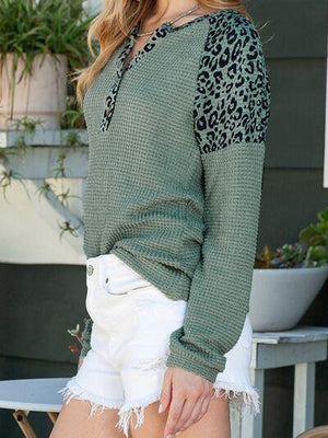 a woman wearing a green sweater and white shorts