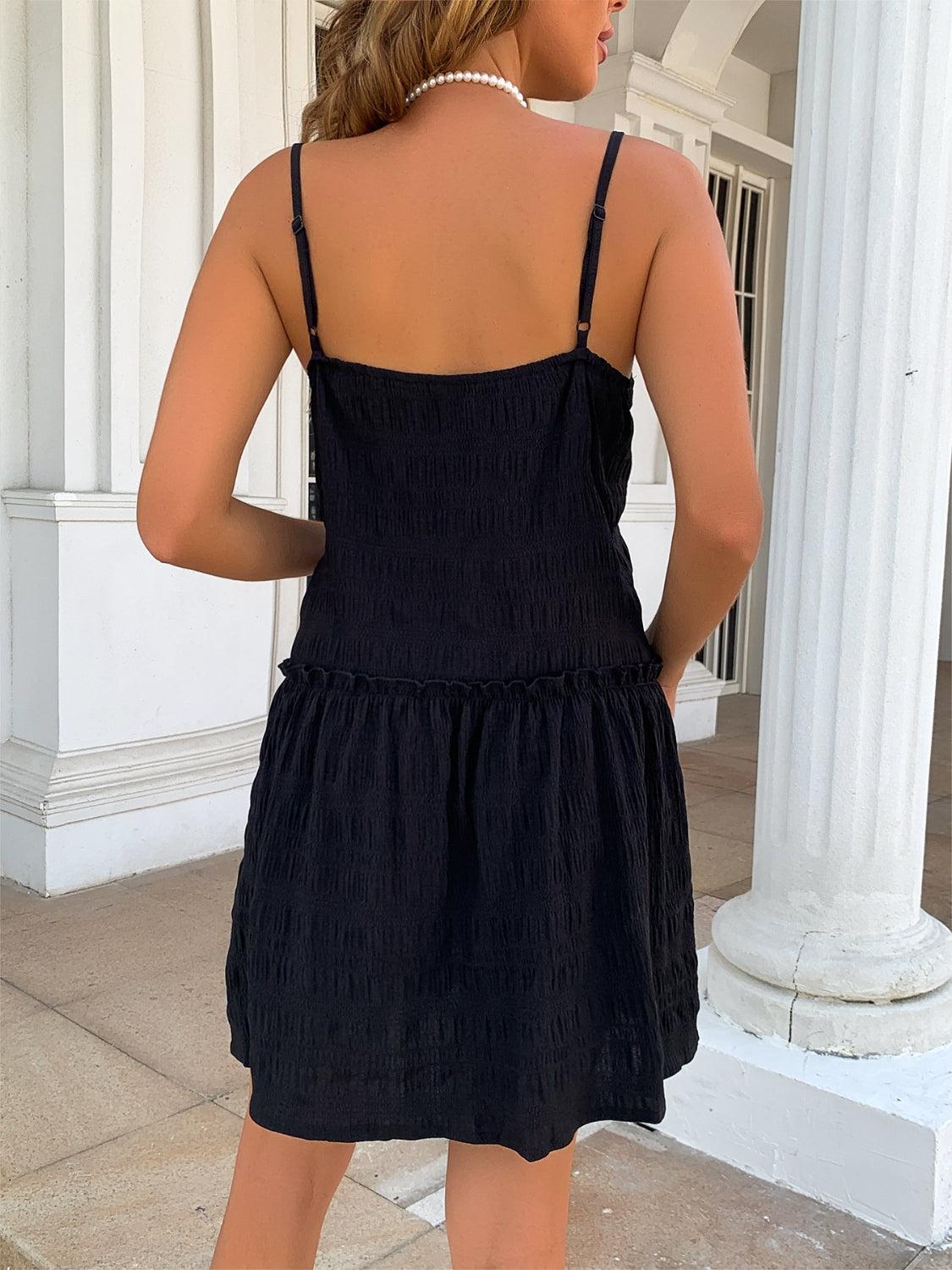 a woman in a black dress standing on a sidewalk