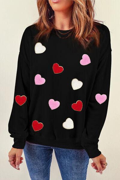 a woman wearing a black sweater with hearts on it
