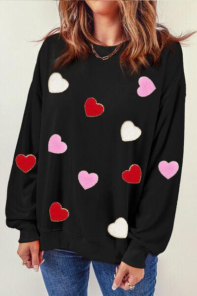 a woman wearing a black sweater with hearts on it