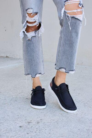 a person wearing ripped jeans and black sneakers