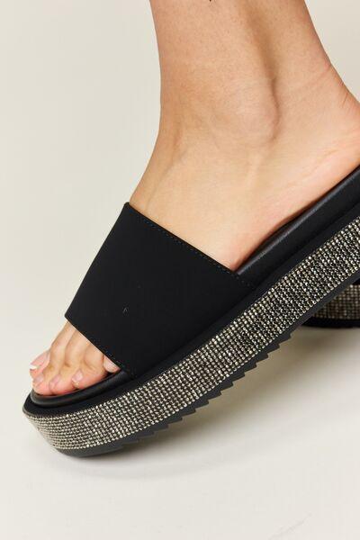 a close up of a person's foot wearing a black platform sandal