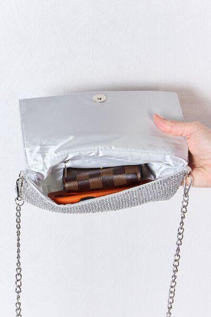 a woman's hand holding a purse with a book inside of it