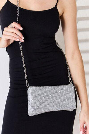 a woman in a black dress holding a silver purse
