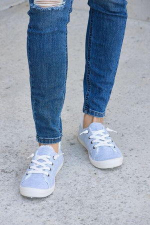a person wearing blue jeans and white sneakers