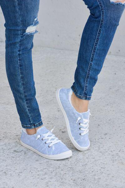 a woman wearing blue jeans and white sneakers