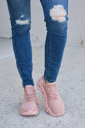a woman in ripped jeans and pink sneakers