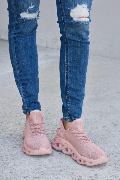 a person wearing ripped jeans and pink sneakers