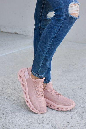 a woman wearing pink sneakers and ripped jeans