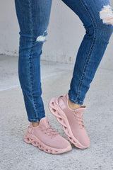a woman wearing pink sneakers and ripped jeans